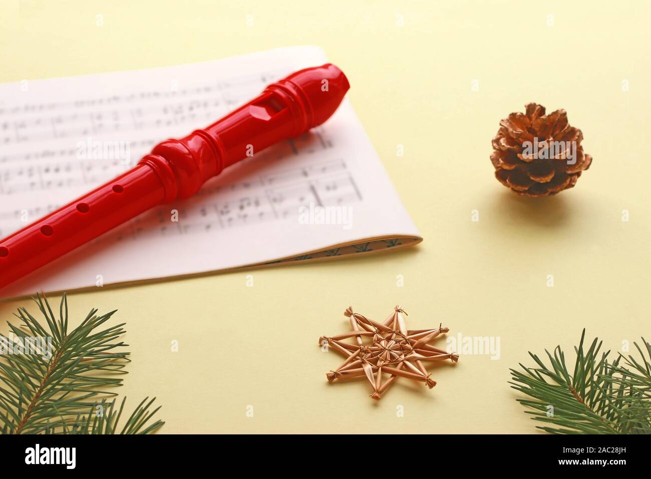 Noël arrière-plan jaune avec un enregistreur rouge posé sur une musique en feuilles, de pommes de pin, de paille et d'étoiles Banque D'Images