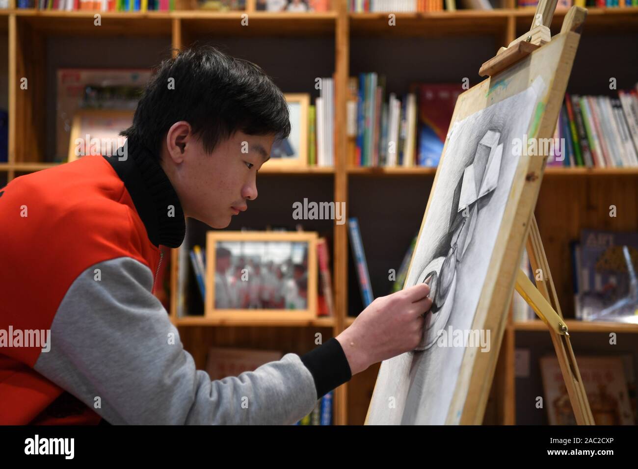 (191130) -- SHANGHAI, le 30 novembre 2019 (Xinhua) -- un Junjun, orphelins touchés par le VIH/SIDA, les peintures à un centre de peinture dans la ville de Fuyang, province de Anhui, Chine orientale, le 25 novembre 2019. C'est difficile de se connecter 18 ans Junjun avec un orphelins touchés par le VIH/SIDA. Étudier dans une école secondaire à Fuyang, le malheureux garçon confiant mais ressemble à ses pairs. Naissance d'un bébé infecté par le VIH en raison de la transmission mère-enfant en 2001, Junjun devenu orphelin en 2004, après que ses parents sont morts du VIH/SIDA. Adopté par l'Association de Fuyang orphelin du SIDA Salut, Junjun a été en mesure de recevoir la même éducation que les enfants Banque D'Images