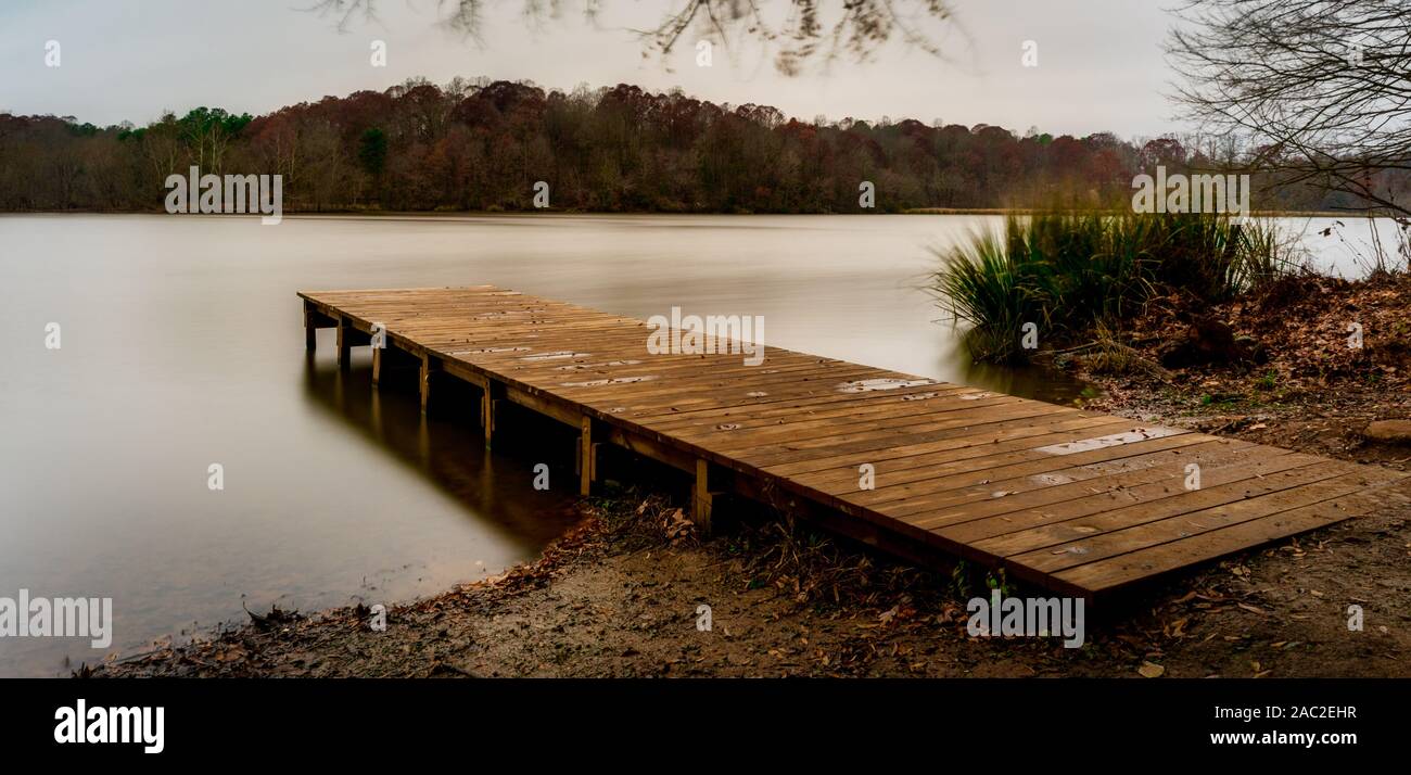 Dock en bois vide menant à un lac lisse à Saxapahaw, North Carolina Banque D'Images
