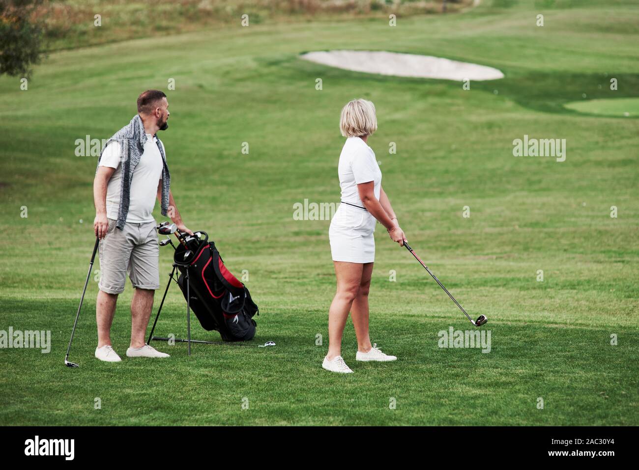 Le suivi de la balle. Couple de joueurs de golf ont une bonne partie de leur temps de fin de semaine Banque D'Images