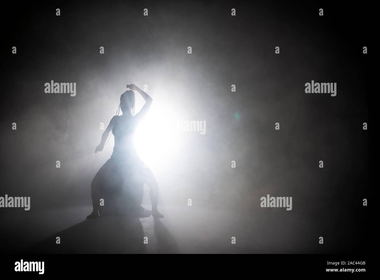 Danseur Silhouette woman performing dance figures dans le brouillard. Banque D'Images