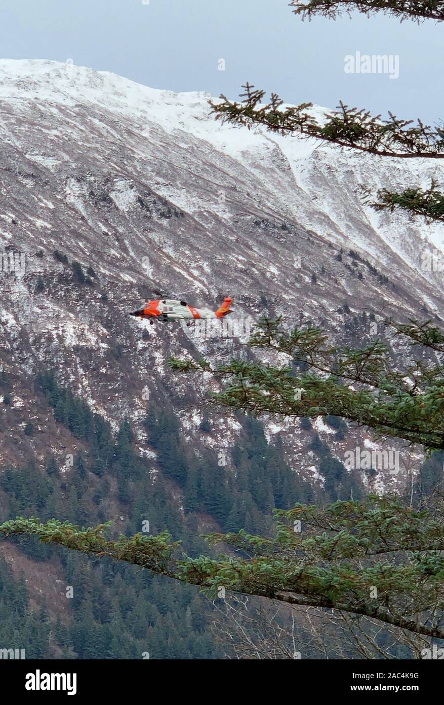 Un équipage d'hélicoptère Jayhawk MH-60 de la Garde côtière Station de l'air effectue une recherche de Sitka le long du canal Gastineau après un navire sans pilote et à la dérive a été trouvé près du pont de Juneau-Douglas, Alaska, le 29 novembre 2019. Un Respond-Boat 45 pieds de l'équipage de la Garde côtière canadienne moyenne de Station Juneau a également contribué à la recherche tandis que le secteur de la Garde côtière canadienne Juneau de quart a pris contact avec le propriétaire du navire et d'autres personnes à bord potentiellement. Photos de la Garde côtière des États-Unis par Lt Cmdr. Scott Shields. Banque D'Images