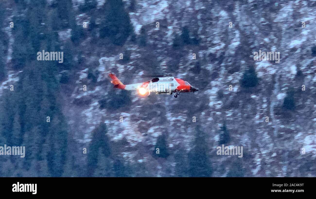 Un équipage d'hélicoptère Jayhawk MH-60 de la Garde côtière Station de l'air effectue une recherche de Sitka le long du canal Gastineau après un navire sans pilote et à la dérive a été trouvé près du pont de Juneau-Douglas, Alaska, le 29 novembre 2019. Un Respond-Boat 45 pieds de l'équipage de la Garde côtière canadienne moyenne de Station Juneau a également contribué à la recherche tandis que le secteur de la Garde côtière canadienne Juneau de quart a pris contact avec le propriétaire du navire et d'autres personnes à bord potentiellement. Photos de la Garde côtière des États-Unis par Lt Cmdr. Scott Shields. Banque D'Images