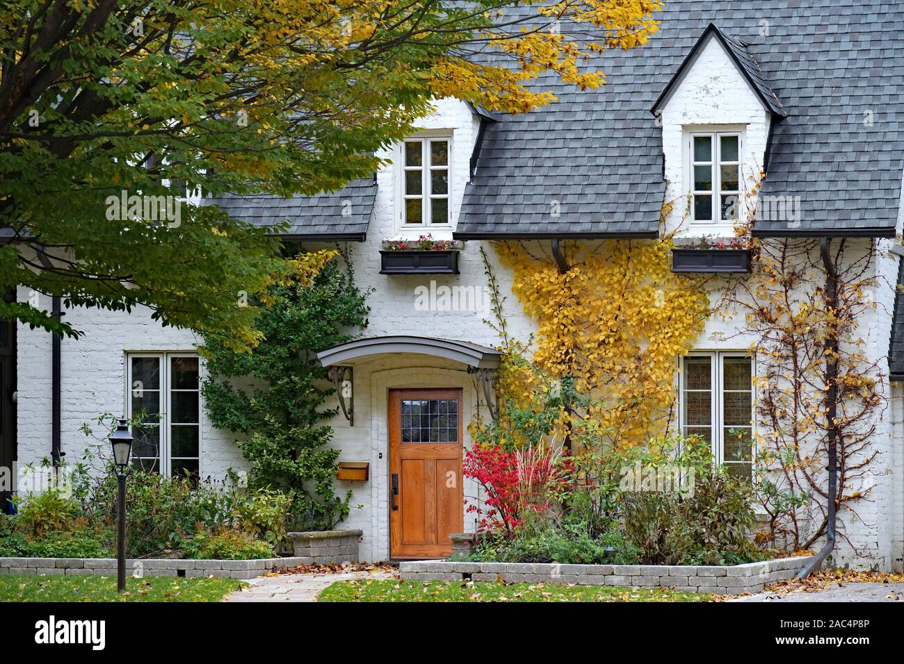 Vieille maison avec des briques peintes en blanc et lucarne avec couleurs d'automne Banque D'Images