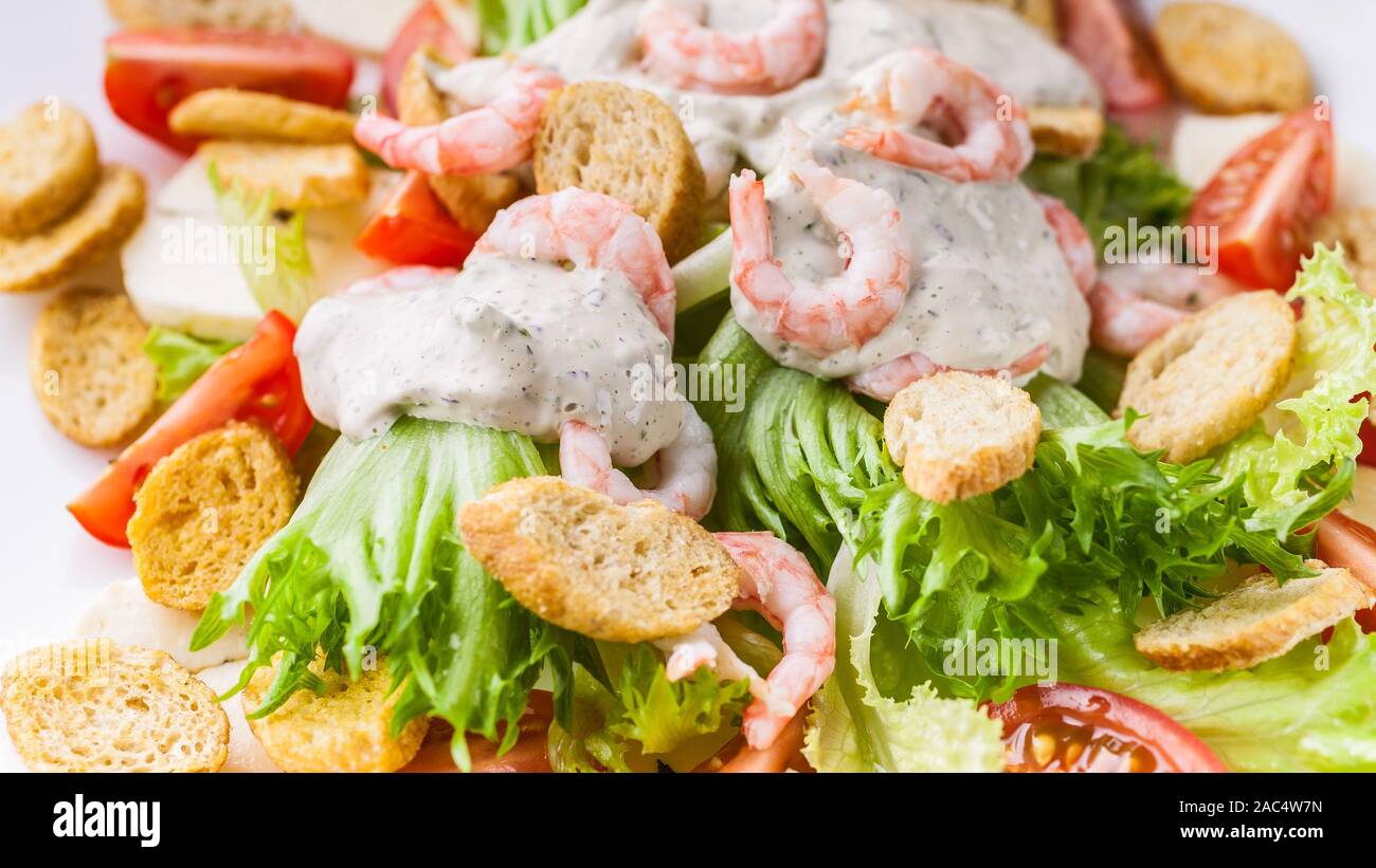 Bannière alimentaire. Close-up appétissante salade avec crevettes, laitue, fromage, avocat et craquelins sur une plaque blanche. Recettes de fruits de mer délicieux et sains. Bas Banque D'Images