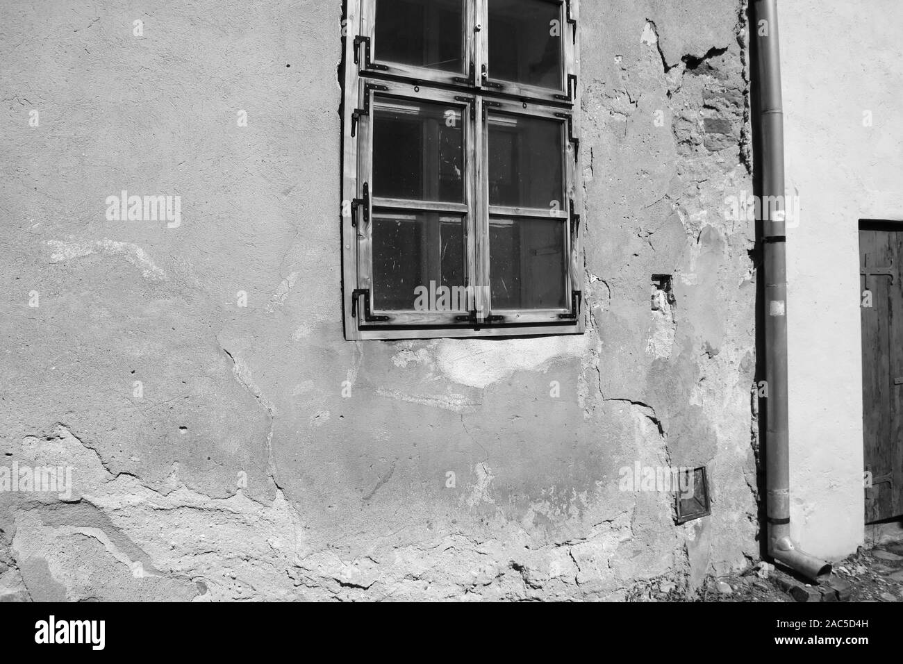 Vue d'une maison ancienne avec des fissures sur le mur et fenêtre, photo en noir et blanc Banque D'Images