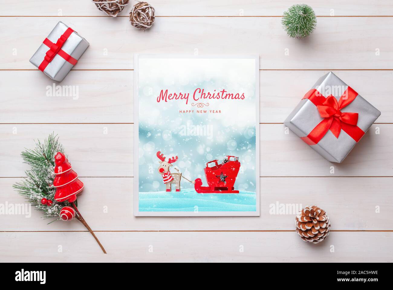 Joyeux Noël et Bonne Année magazine sur le bureau en bois blanc entouré de décorations et cadeaux de Noël Banque D'Images