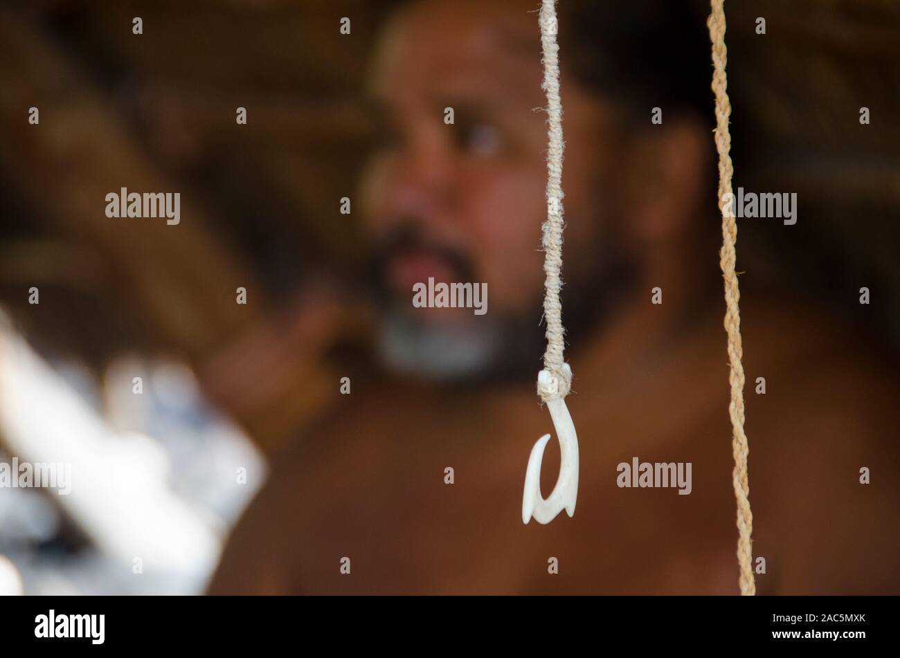 Un gros plan d'un hameçon avec un hawaiien homme derrière elle à Pu'uhonua o Honaunau (Ville de Refuge), Kona, Big Island du Sud Banque D'Images