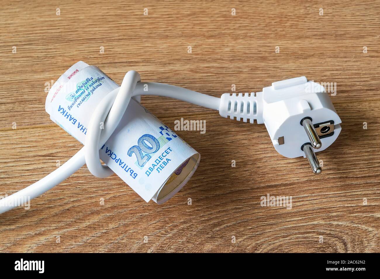 Câble électrique avec fiche lié à un noeud sur un rouleau de lev bulgare  des billets en euros. Coût de l'électricité et l'énergie coûteuse des  concepts. Sur une surface en bois Photo