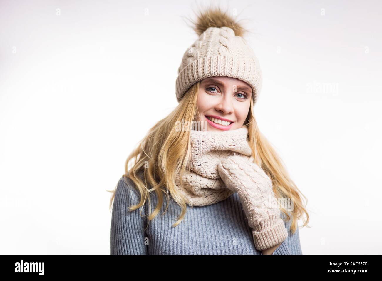 Hiver close-up portrait of attractive young blonde woman wearing hat  tricoté chaud beige avec pompon en fourrure et écharpe snood. Girl looking  at camera sur wh Photo Stock - Alamy