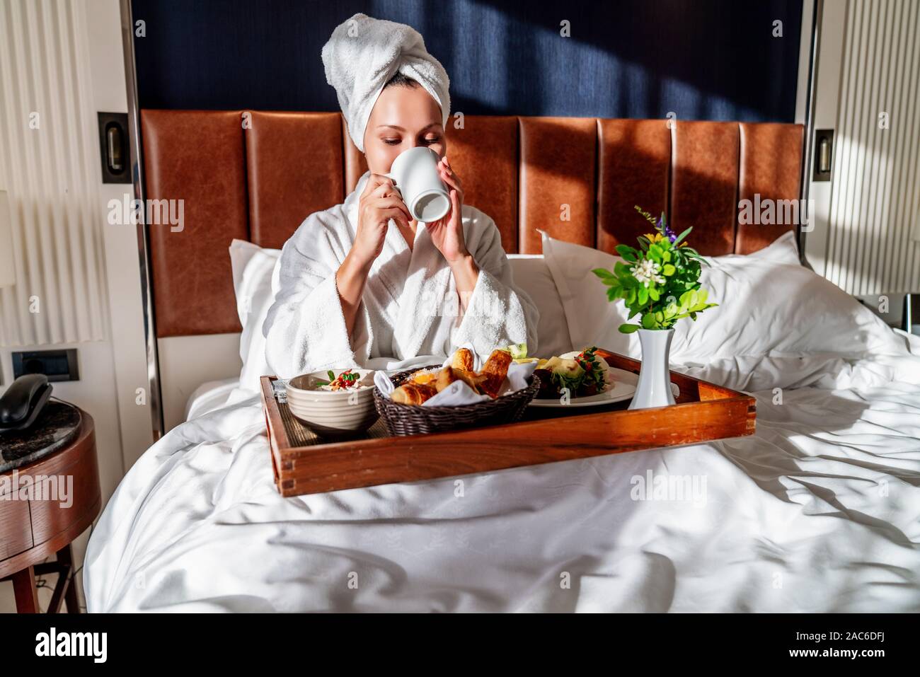 Femme ayant le petit déjeuner dans un lit confortable et de boire du café. Banque D'Images