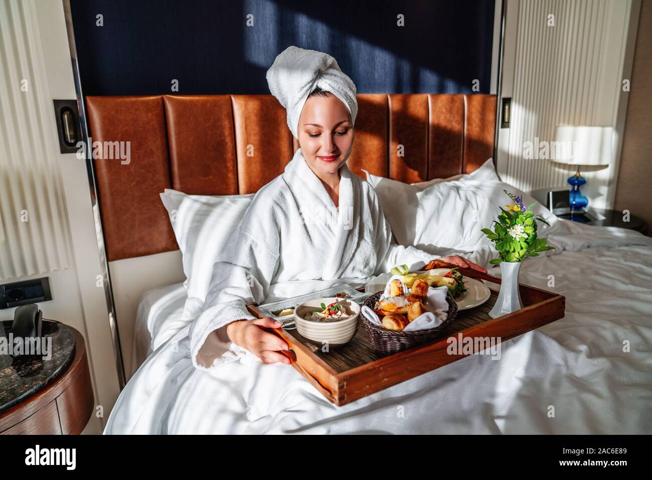 Jeune femme qui a son petit déjeuner au lit avec plaisir. Banque D'Images