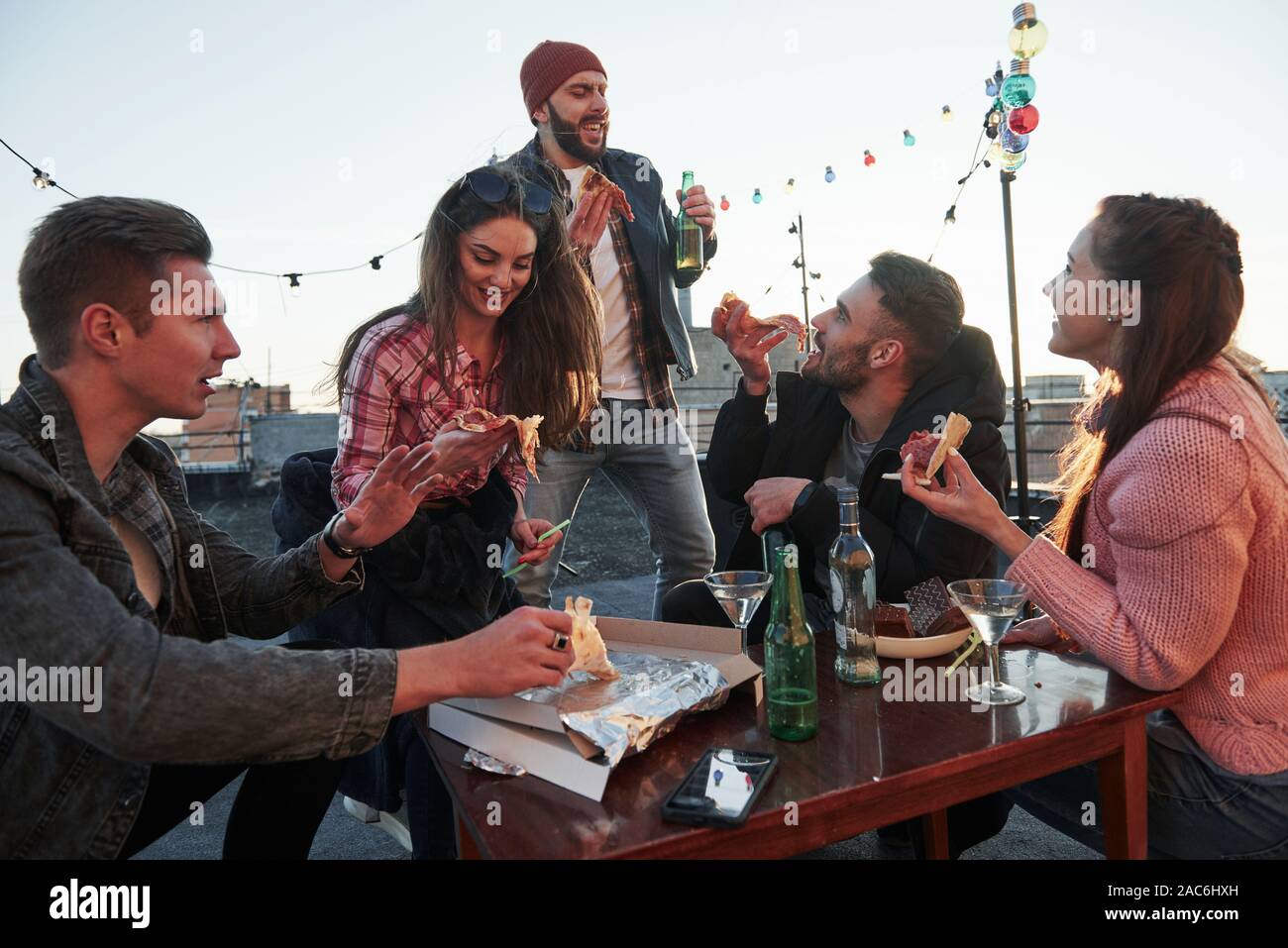 Temps pour le chant. Au moins guy dans Red Hat croit que oui. Manger une pizza à la soirée sur le toit. Bon week-end avec des amis ont une délicieuse nourriture et alcool Banque D'Images