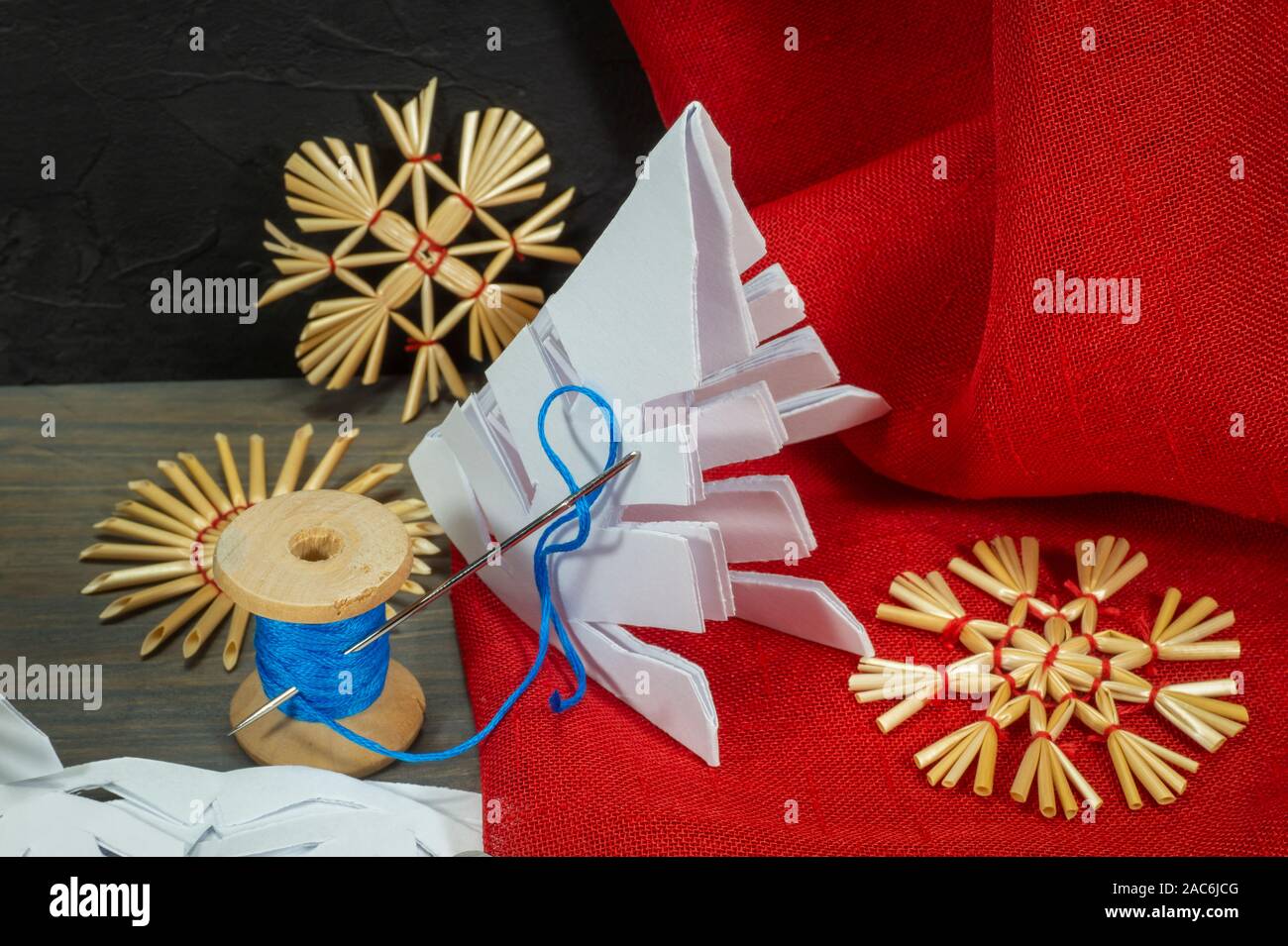Fond Noël fête avec des décorations de Noël à partir de paille, de bonneterie chaîne et aux côtés du papier tissu rouge et une paire de ciseaux Banque D'Images