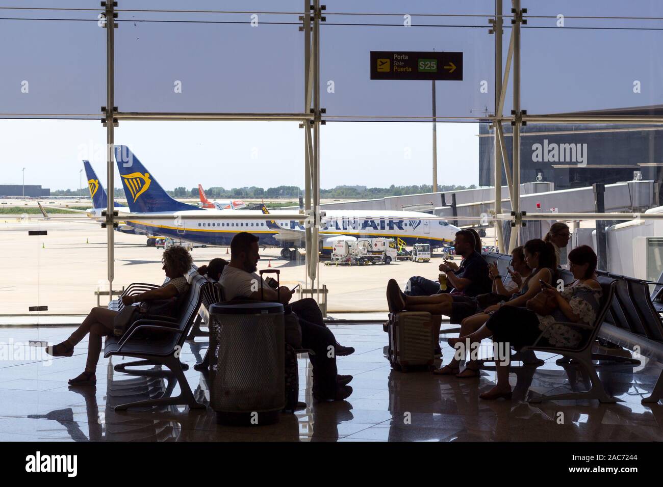 Barcelone, Espagne - 11 août 2019 : Les passagers qui attendent à la porte d'embarquement à l'aéroport, avec un avion de Ryanair en arrière-plan Banque D'Images