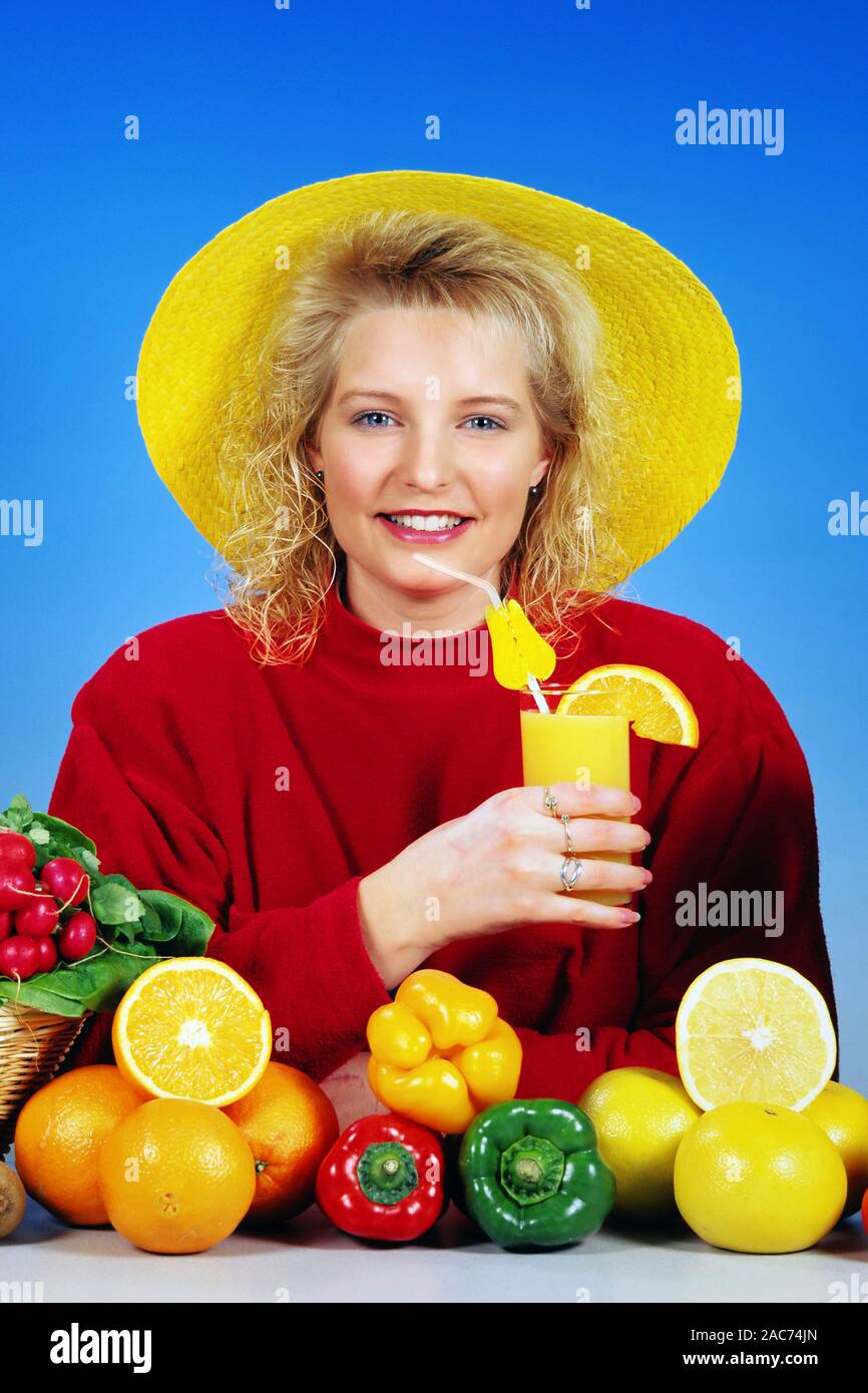 Blondes Maedchen, Gelber, Orangensaft Strohhut trinkt, im Vordergrund verschiedene Obst und, Gemuesesorten Modelrelease Studioaufnahme, vorhanden, Banque D'Images