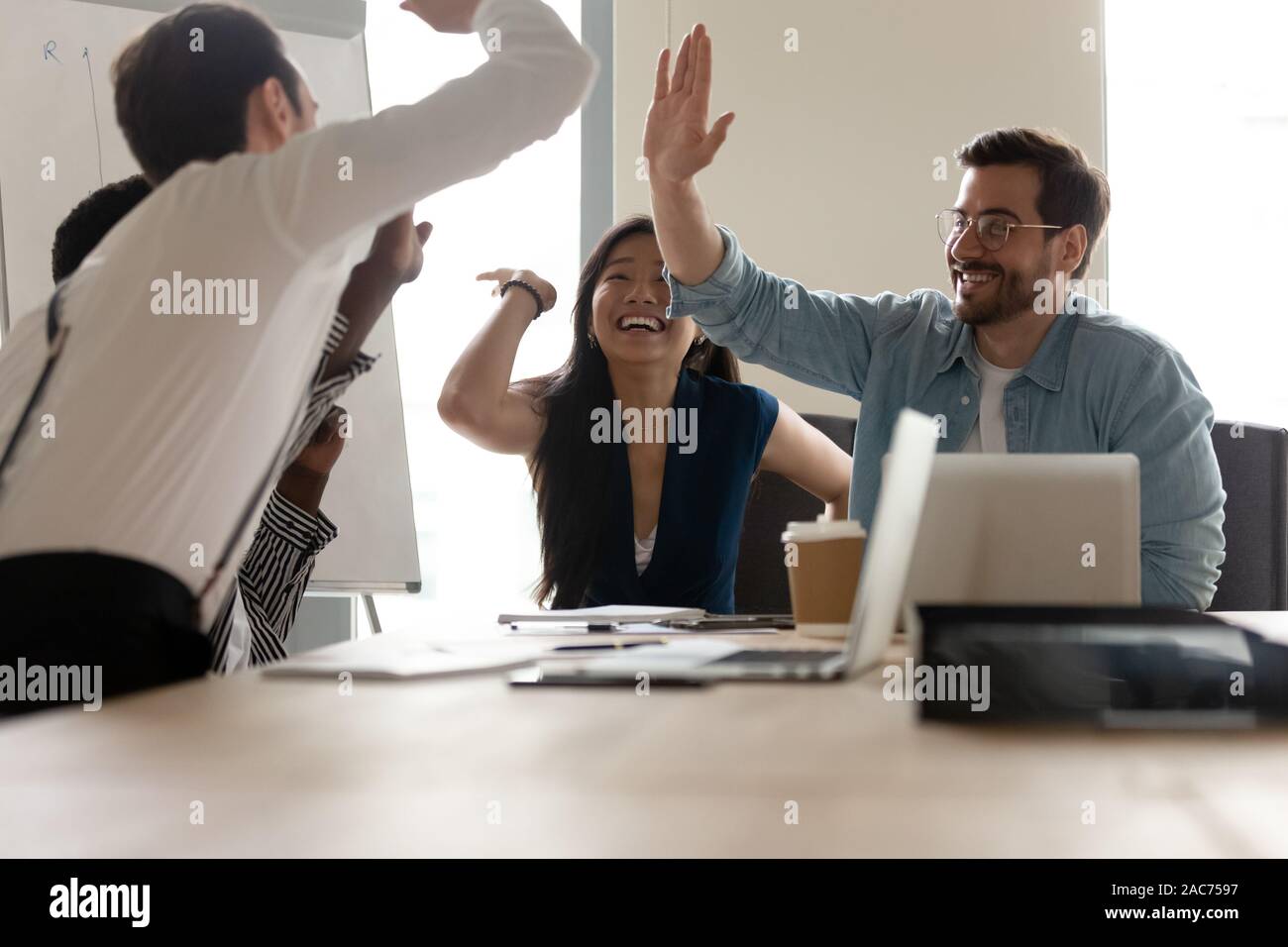 Multi-ethnic businesspeople offrant un rapport cinq célébrant la fermeture affaire rentable Banque D'Images