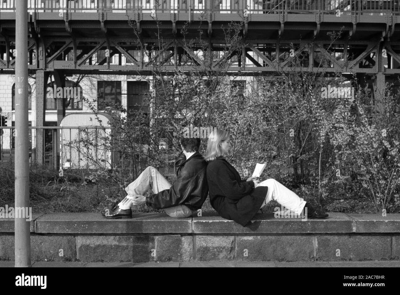 Film en noir et blanc photographie d'un couple assis dos à dos sur un muret, pas au courant de l'appareil photo, sur Johannisbollwerk, Hambourg, Allemagne, vers 1990 Banque D'Images