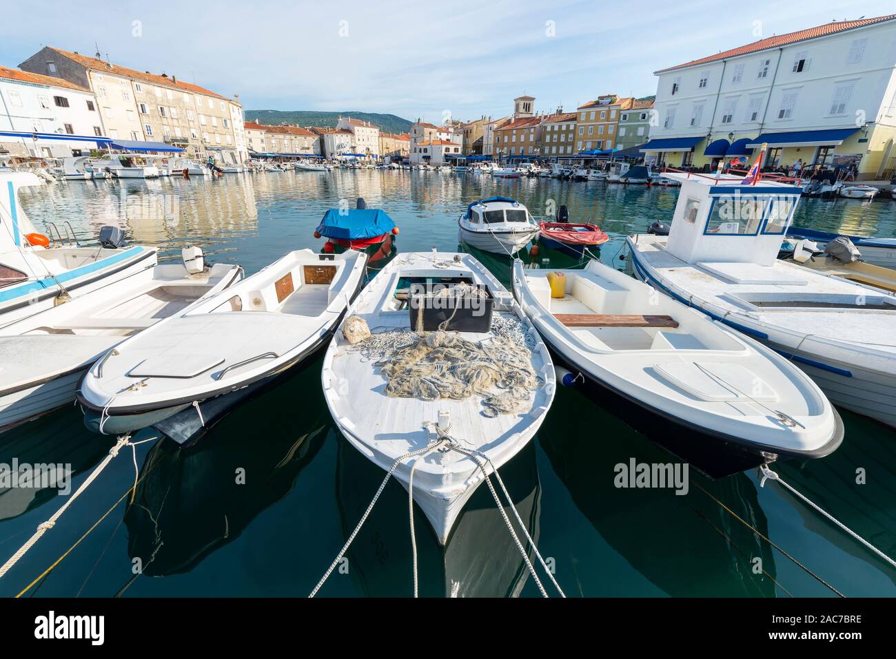 Les bateaux de pêche et bateaux à moteur dans le port de la vieille ville de Cres avec façades colorées de cafés et restaurants dans le soleil du matin, Croatie Banque D'Images