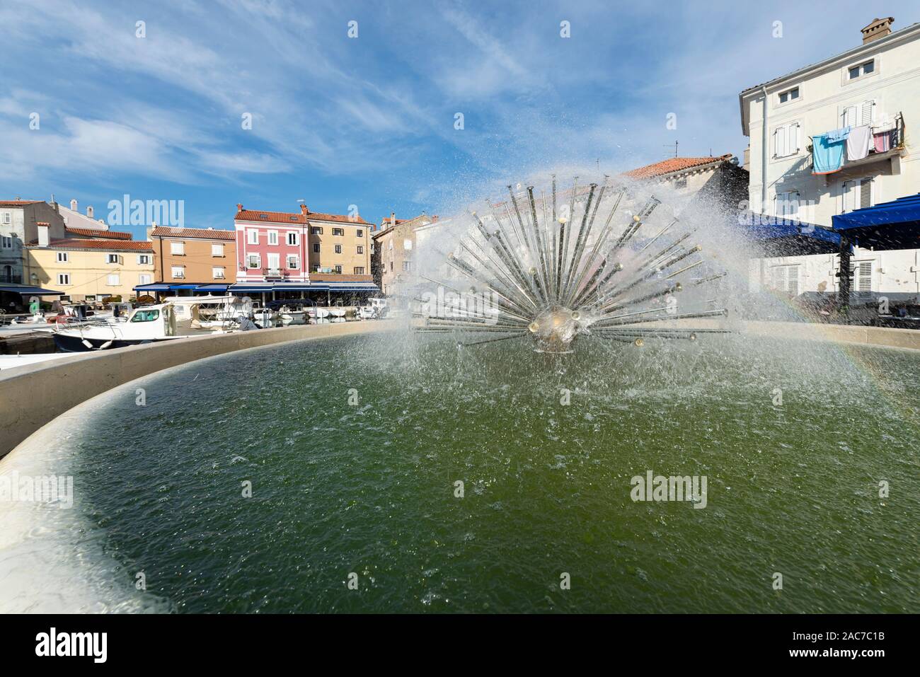 Fontaine sphérique dans le port de la vieille ville de Cres avec cafés et restaurants dans le soleil du matin, Cres, la baie de Kvarner, Croatie Banque D'Images