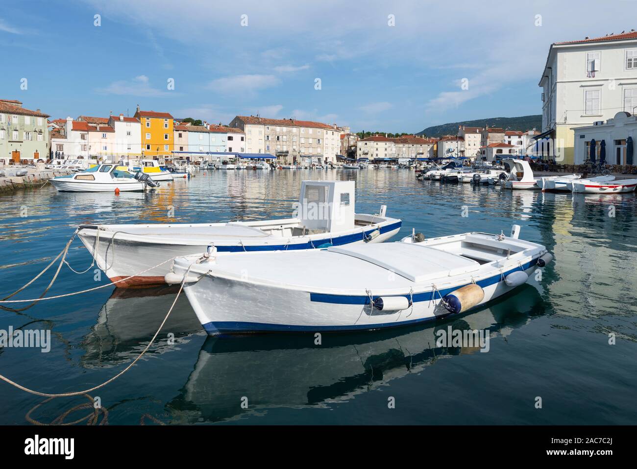 Les bateaux de pêche et bateaux à moteur dans le port de la vieille ville de Cres avec façades colorées de cafés et restaurants dans le soleil du matin, Croatie Banque D'Images