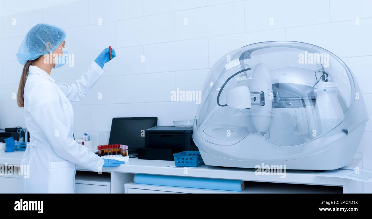 Femme en vêtements médicaux à la recherche au sang en tube à essai Banque D'Images