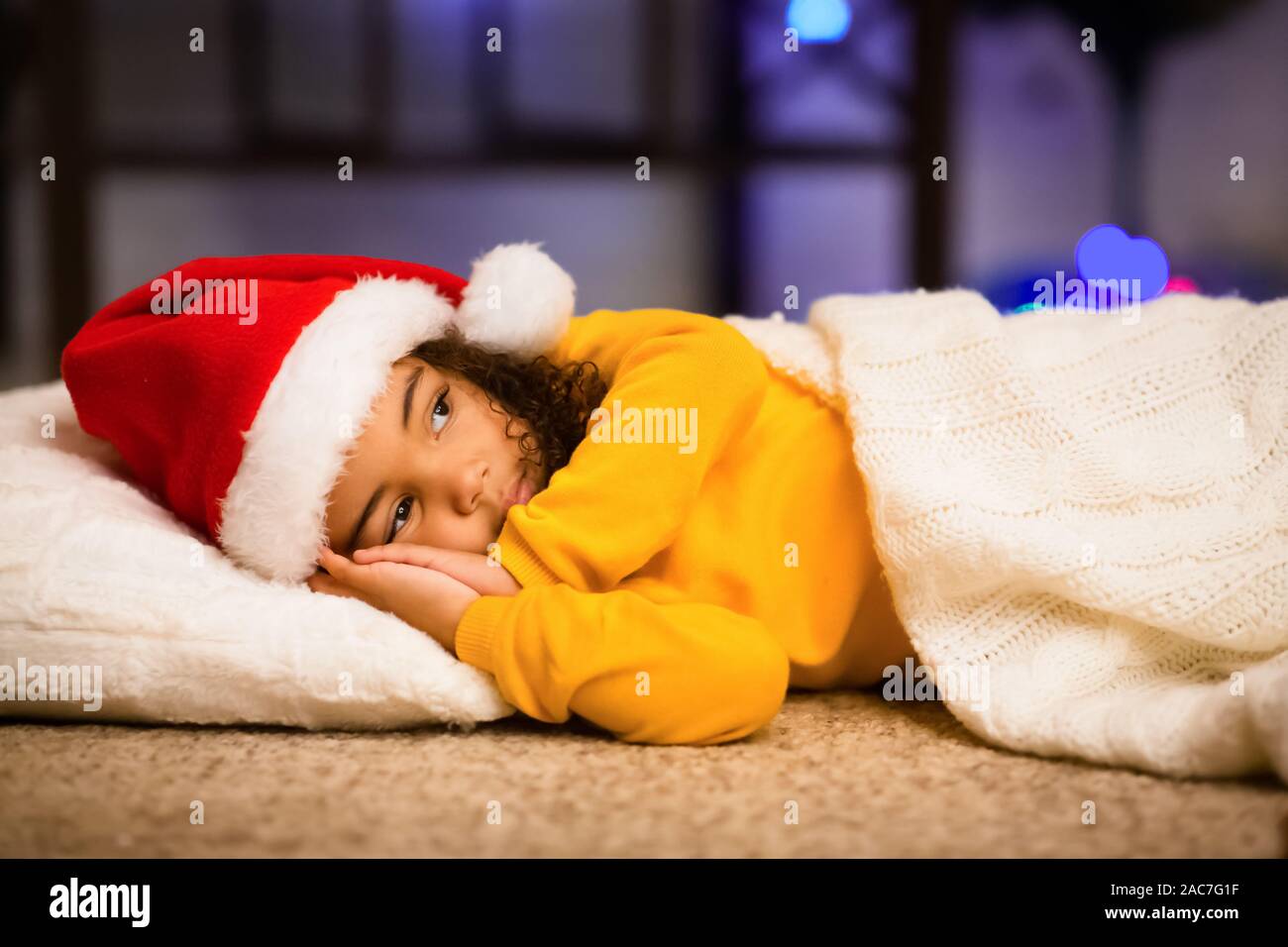 Peu d'african girl prétendant dormir, en attente de Santa sur plancher Banque D'Images