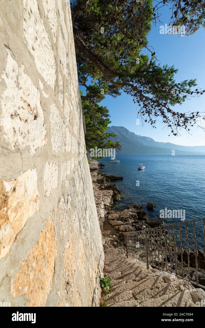 Escaliers vers le bas aux rochers sur l'eau en dessous de la muraille de la ville de Korcula avec vue sur la mer et les montagnes de Peljesac, Dalmatie, Croatie Banque D'Images