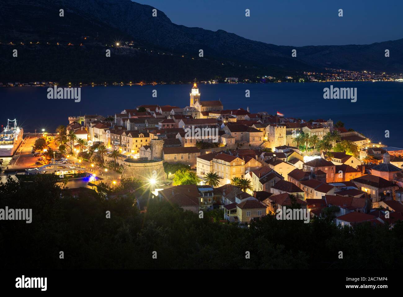 Vue sur les rues médiévales et les bâtiments de la vieille ville historique de Korcula en face de l'île de Peljesac après le coucher du soleil, la Croatie Banque D'Images