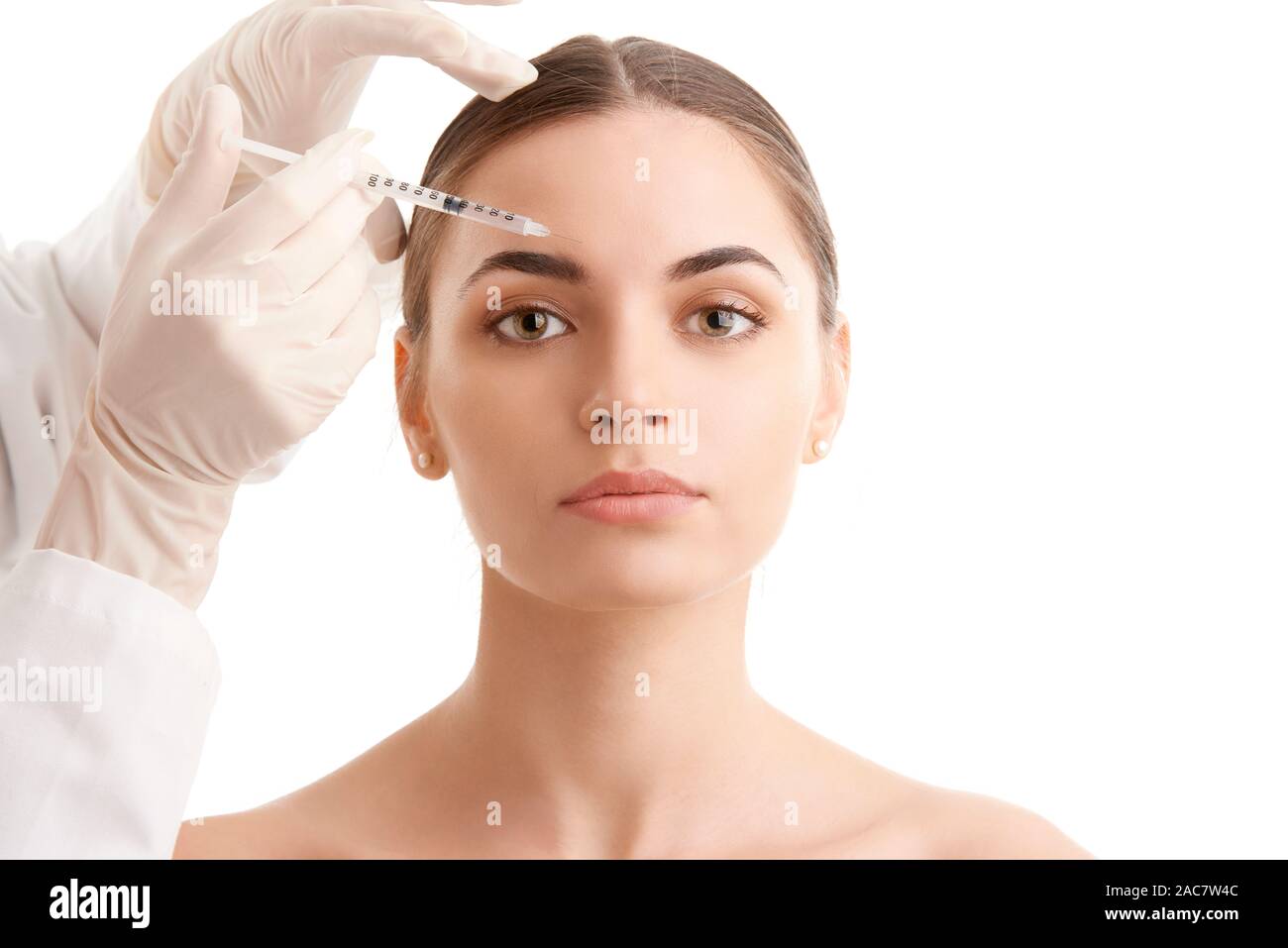 Portrait d'une jolie jeune femme qui reçoit un traitement de botox. Isolé sur fond blanc. Banque D'Images