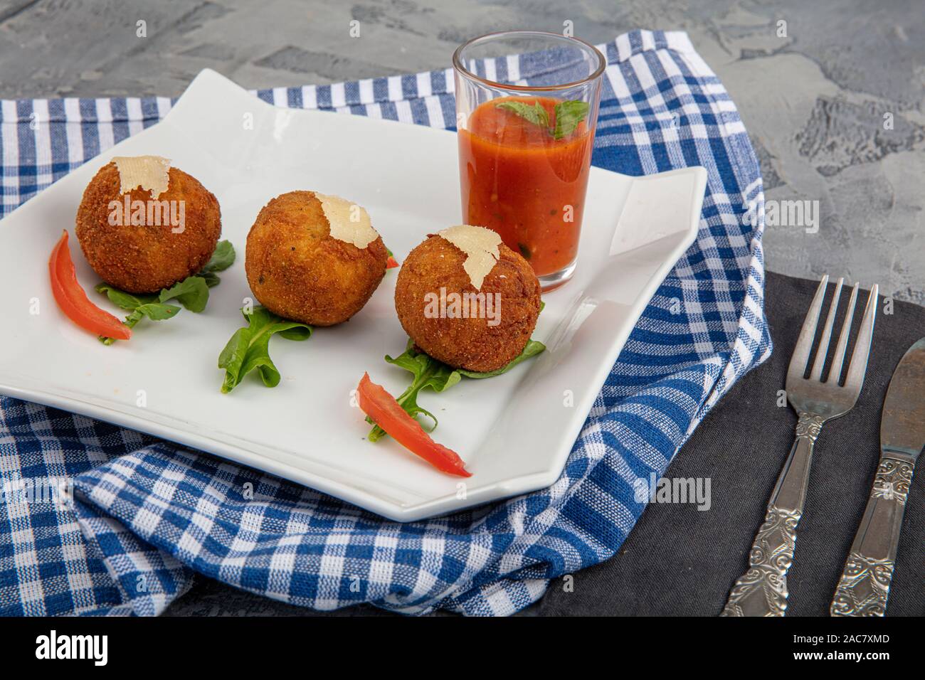 Arancini - délicieux arancini italiens chauds. Safran boulettes de riz farcies de fromage fondu recouvert de fromage râpé parmesan et roquette rectangulaire sur Banque D'Images