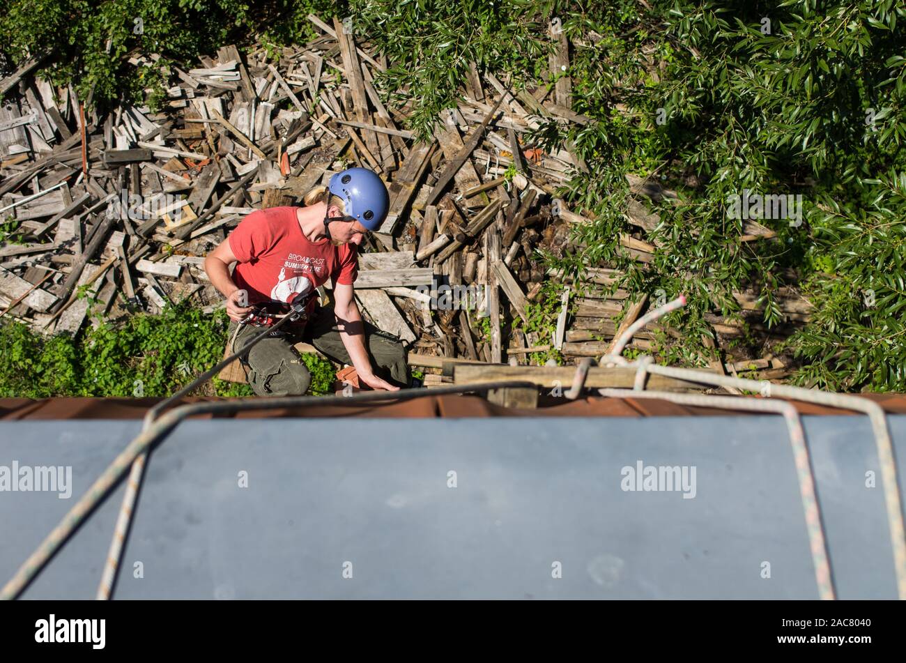 Jeune homme de harnais d'escalade travaillant sur le toit Banque D'Images