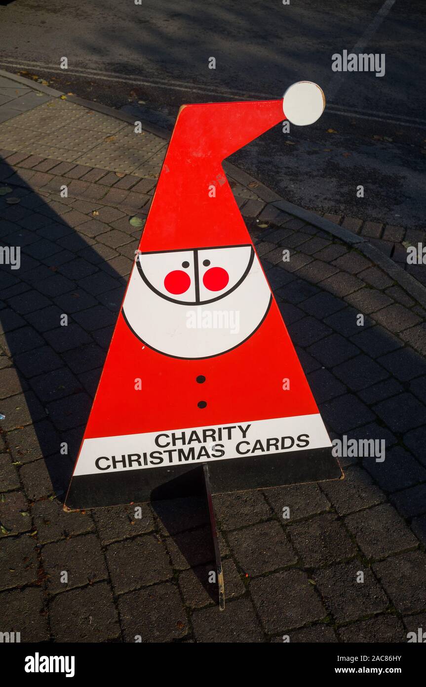 Un rouge lumineux et blanc cartes de Noël de charité panneau dans la forme stylisée d'un Père Noël en plein soleil Banque D'Images