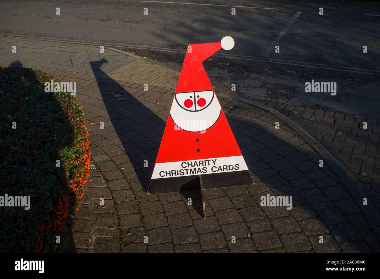 Un rouge lumineux et blanc cartes de Noël de charité panneau dans la forme stylisée d'un Père Noël en plein soleil Banque D'Images