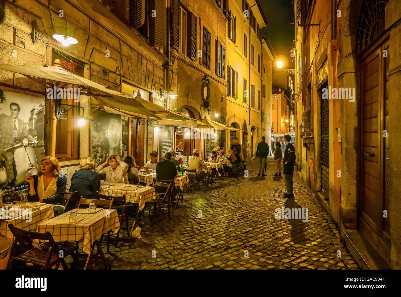 Une rue résidentielle typique de Rome, où les gens sont à l'extérieur manger dans un petit restaurant du quartier sur une rue pavée. Banque D'Images