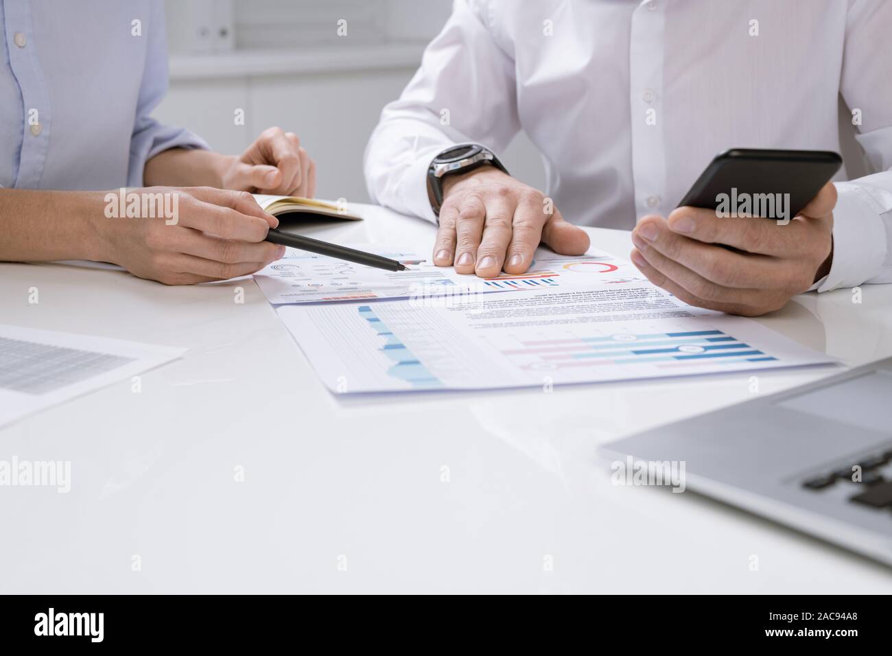 Mains d'économistes contemporains discuter tableau financier sur le papier alors que l'un d'eux pointant sur le document Banque D'Images