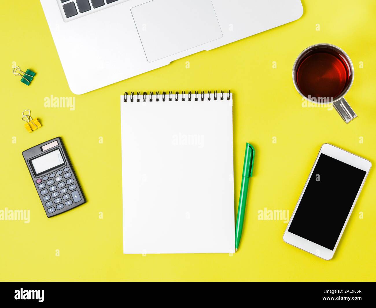 Création moderne d'un jaune vif d'un bureau avec ordinateur portable, smartphone et autres accessoires. Blank Notepad page pour le texte au milieu, vue d'en haut. Banque D'Images