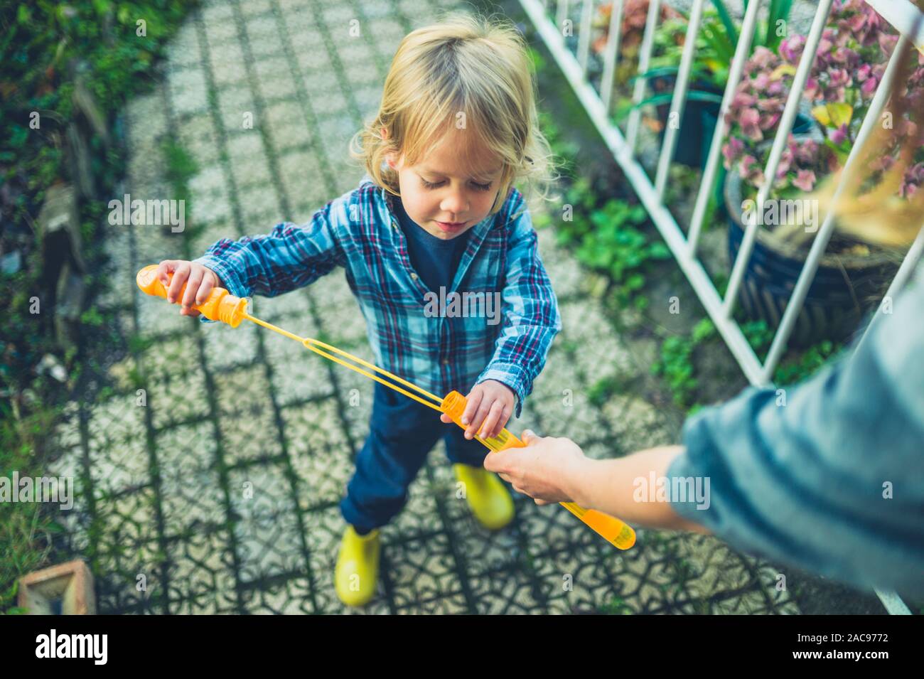Un peu de tout-petit est faire des bulles dans le jardin avec sa mère Banque D'Images