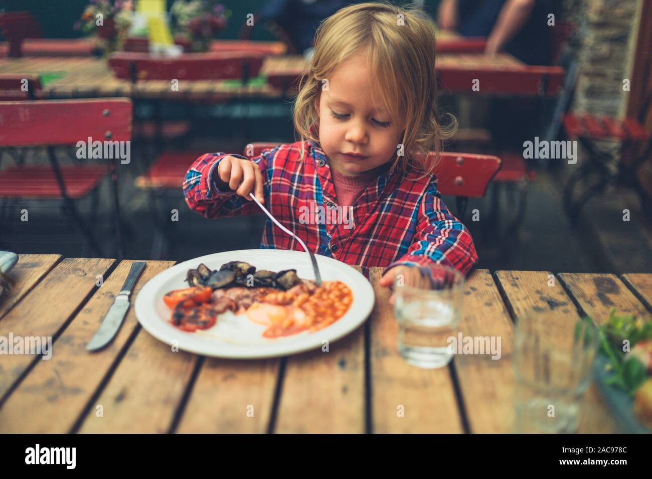 Un petit enfant est en train de manger un petit-déjeuner anglais chaud dans un café Banque D'Images