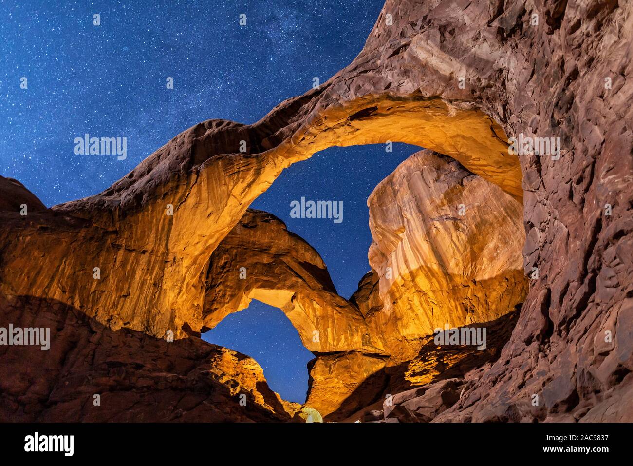 La lune et la lumière artificielle, combiner à la lumière jusqu'à l'Arcade Double Arches National Park, Utah. Banque D'Images