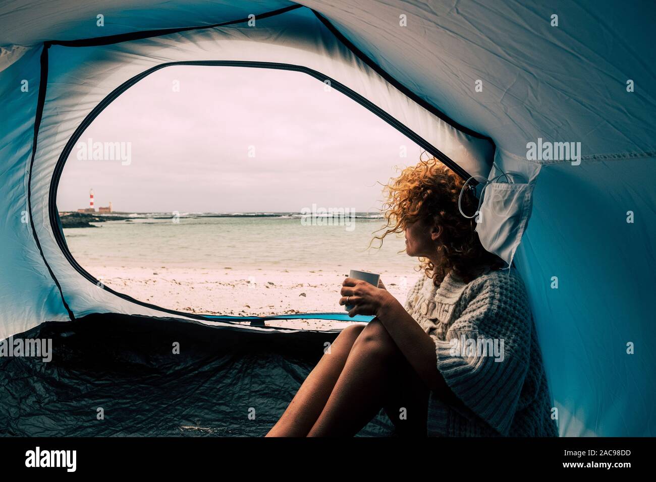 Caucasian woman indépendant jouissant de la liberté de l'aventure à l'intérieur d'une tente de camping sur le sable.. à la plage - vue sur l'océan et pas de stress Banque D'Images
