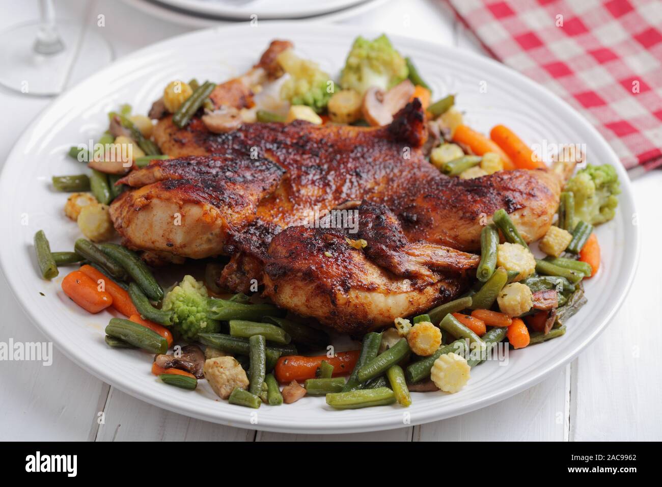 En vertu d'un poulet, de brique ou de pollo al mattone, avec des légumes grillés sur un grand plat blanc Banque D'Images