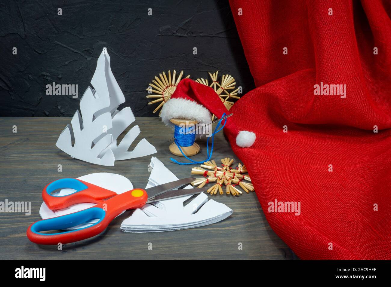 Fond Noël fête avec des décorations de Noël à partir de paille, de bonneterie chaîne et aux côtés du papier tissu rouge et une paire de ciseaux Banque D'Images
