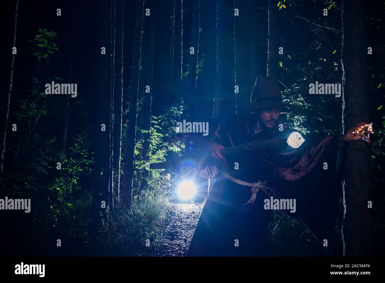 Jeune Magicien dans costuem effectuer acrobat se déplace dans la forêt sombre Banque D'Images