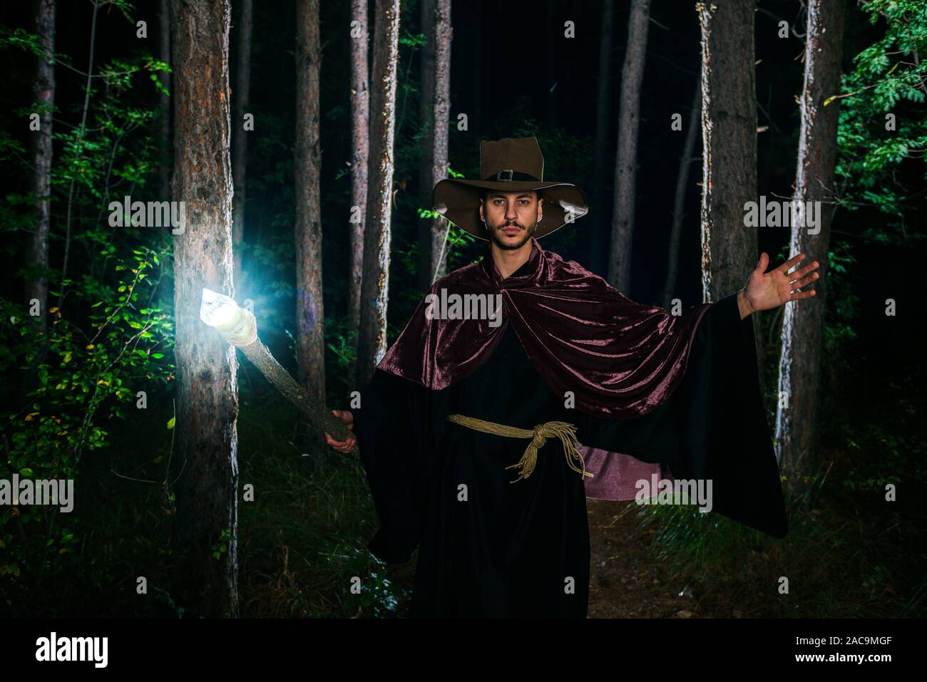 Jeune Magicien dans costuem effectuer acrobat se déplace dans la forêt sombre Banque D'Images