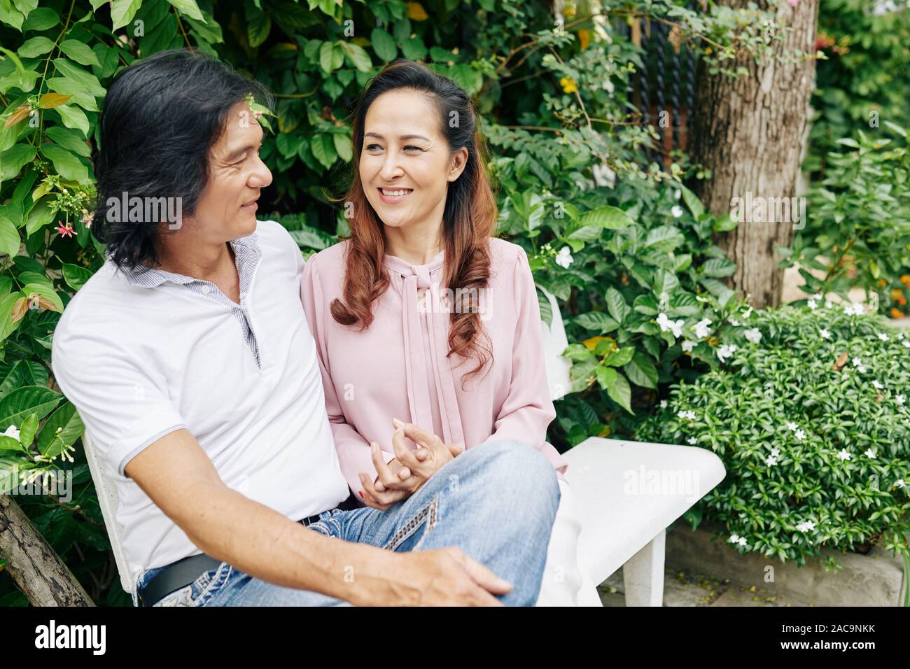 Smiling mature couple amoureux assis sur un banc, discuter et profiter de date romantique Banque D'Images