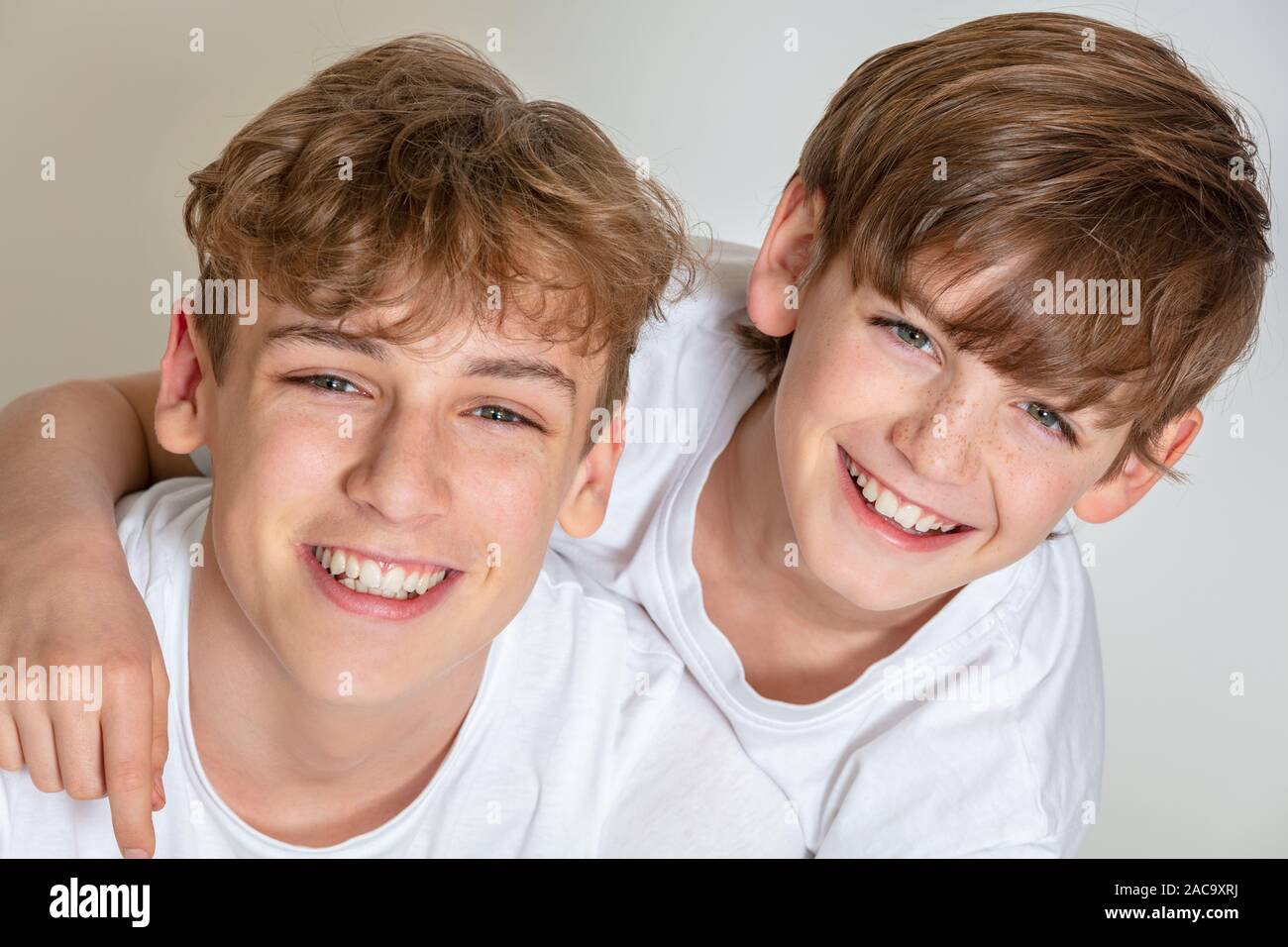 Fond blanc photographie de jeune garçon heureux frères enfants vêtus de t-shirts et souriant avec dents parfaite Banque D'Images