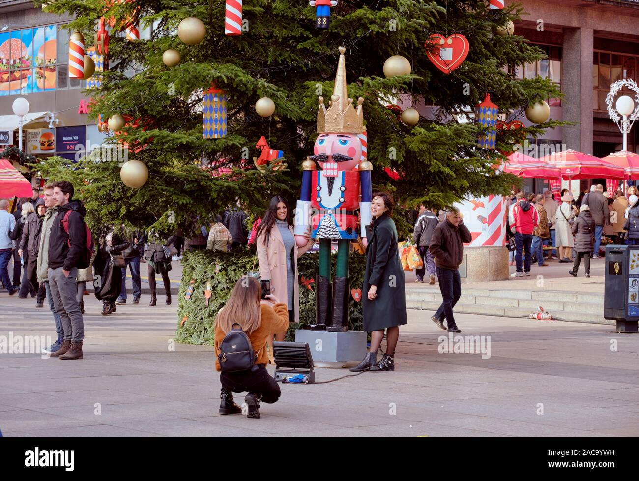 Deux jolies dames posant à côté d'une des statue Casse-noisette à côté de grand arbre de Noël en place au centre du marché de l'Avent. Zagreb, Croatie Banque D'Images