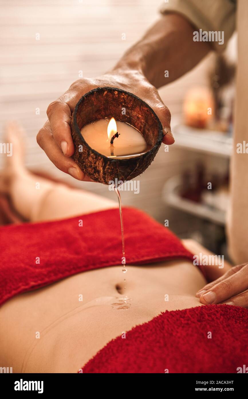 Salon de médecine alternative guérison thérapeute Femme allongée avec  massage bougie arôme éclairé verser de la cire chaude sur son ventre  close-up Photo Stock - Alamy