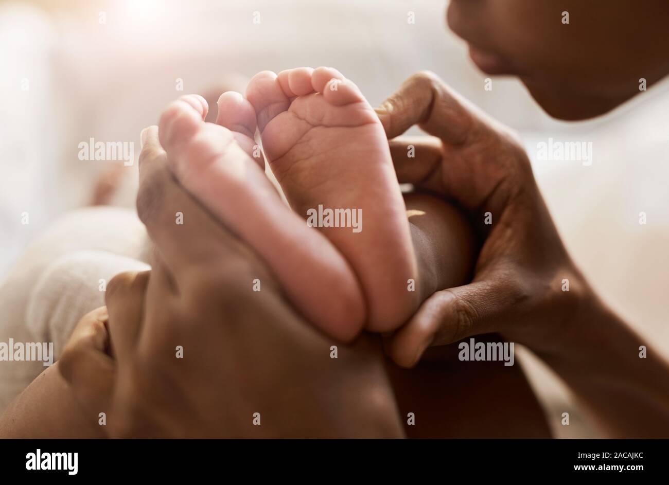 Close up portrait of African-American woman holding petits pieds de mignon bébé dans la lumière du soleil, copy space Banque D'Images